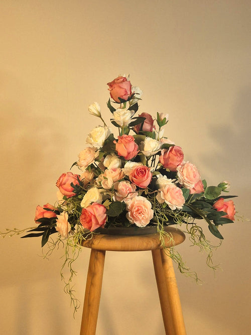 Eksklusiv lounge dekoration med ferskenfarvede og hvide roser på en træpædestal. Vedligeholdelsesfri atmosfære til erhverv.